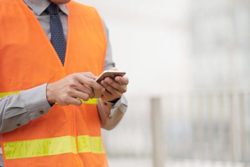 Foreman sending instructions via smartphone